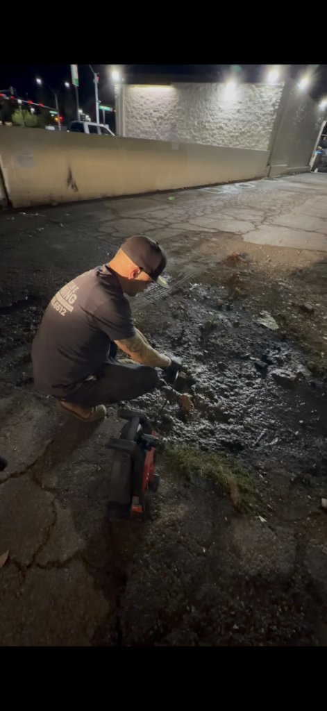 Pristine Plumbing technician working at a sewer repair access area